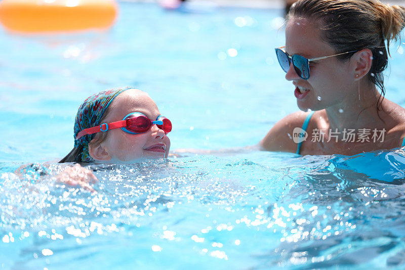 女教练在游泳池里教小女孩游泳