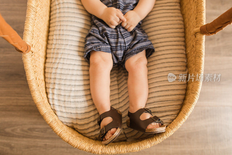 一个21周大的男婴的脚有12个脚趾，躺在舒适的纱布棉毯上，在海草摩西篮子里