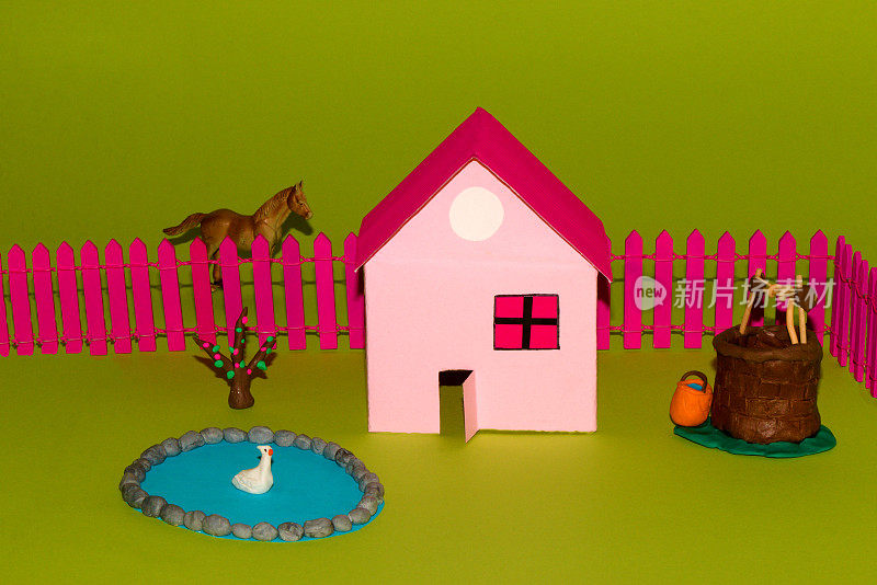 带喷泉井和粉红色围栏的乡村别墅，草地放牧的马，创意设计纸村