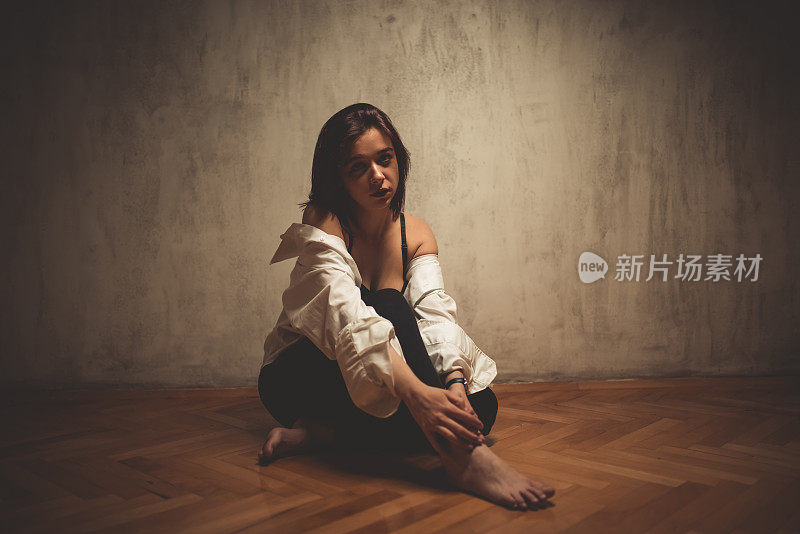 穿着内衣的年轻女人坐在地板上