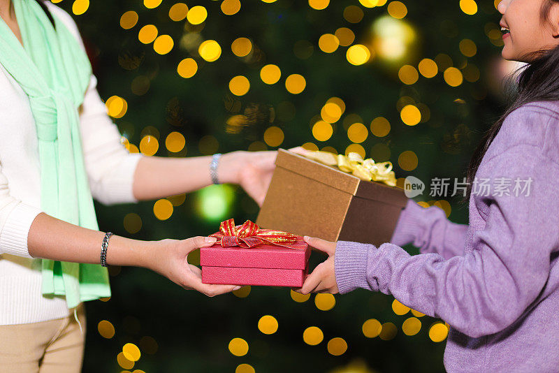 母亲在圣诞节或除夕夜给女儿一个特别的惊喜。惊喜的礼物概念，母亲与孙女交换圣诞和新年礼物盒