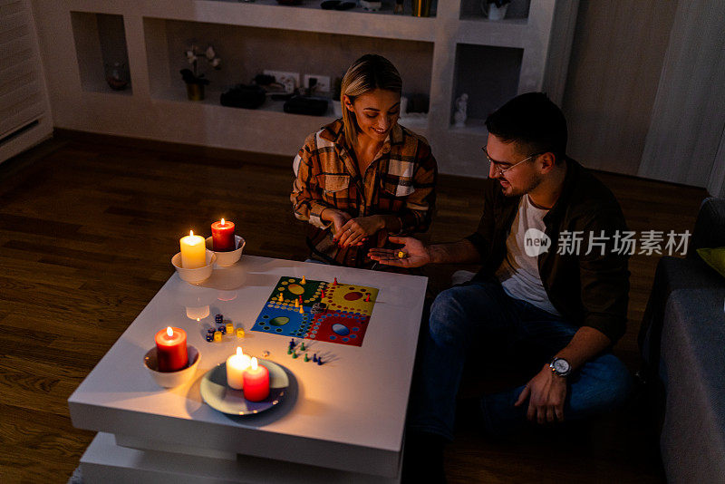 在一次精力充沛的危机中，一对年轻夫妇在黑暗中点着蜡烛玩卢多游戏。