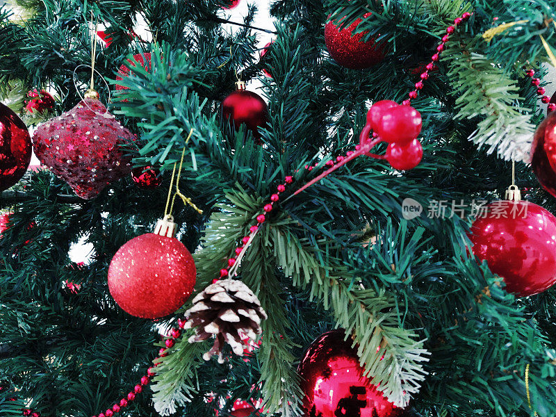 有装饰品、圣诞球和玩具的圣诞树。红白相间的挂饰。漂亮的球，明亮的浆果和球果。