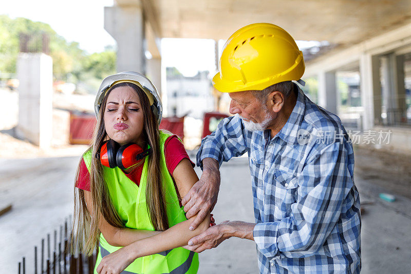 年轻的女建筑工人在建筑工地受伤，她的资深同事正在帮助她。