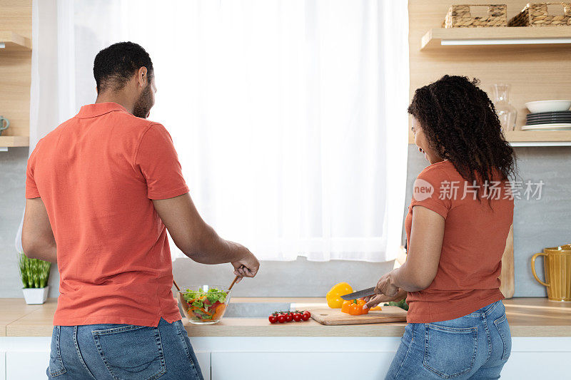 年轻的非裔美国夫妇穿着同样的t恤和蔬菜一起做饭
