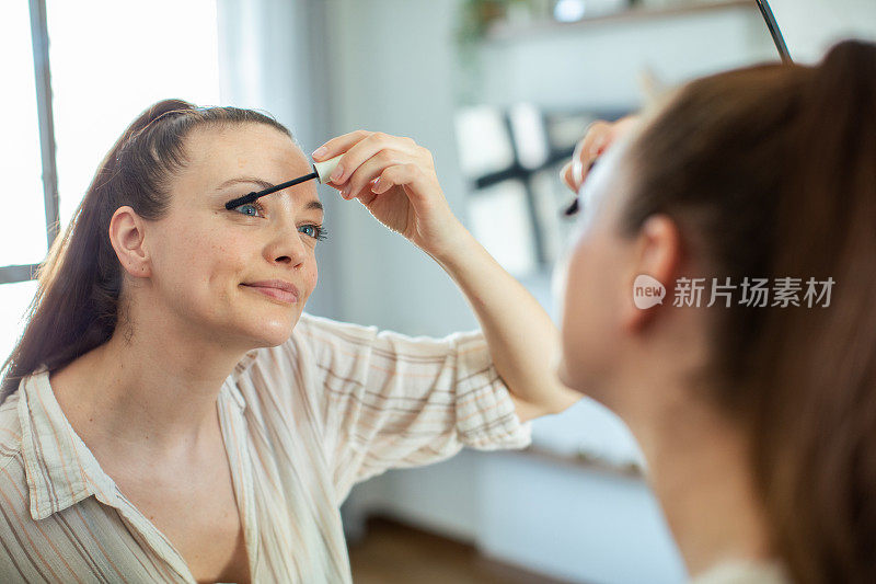 年轻女子在家里对着镜子化妆