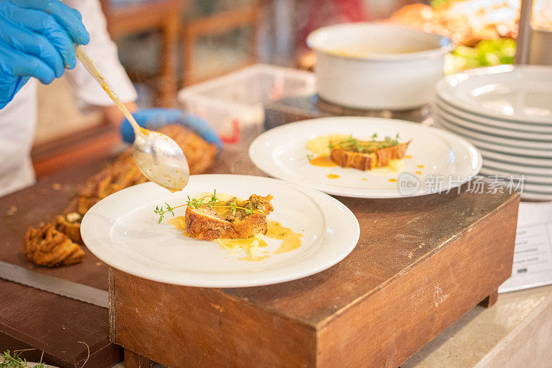 在酒店或餐厅的厨房里，厨师用手把酱汁倒在盘子里，