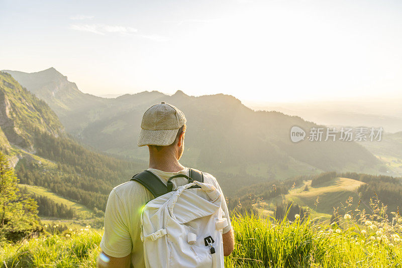 一名男子在日出时沿着长满草的山脊徒步