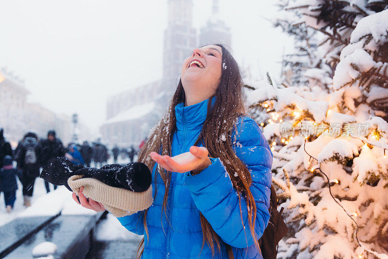 快乐的女人背着背包，在克拉科夫思考下雪的圣诞节