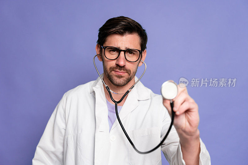 蓝色背景的医生手持听诊器的肖像。