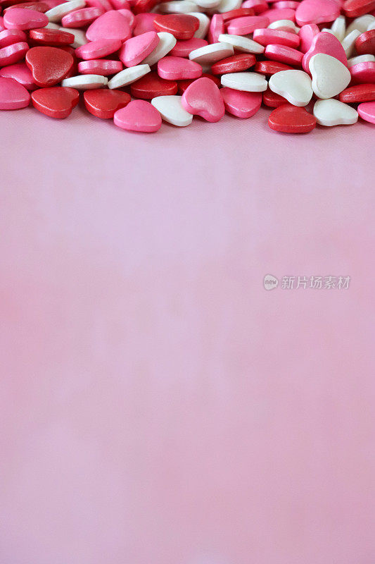 形象情人节设计海报框架由红色、粉色和白色心形糖果打造，情人节装饰，斑驳的粉色背景，抬高视野，情人节和浪漫的概念，复制空间