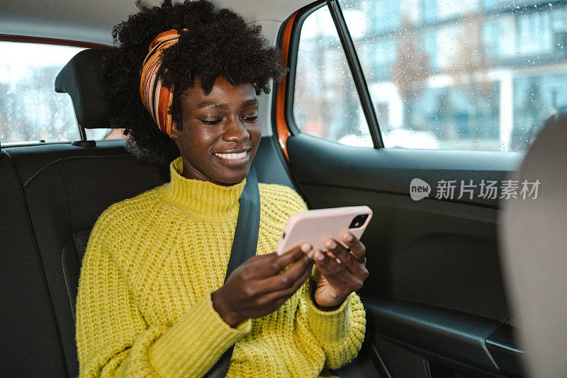 年轻女子在出租车上用智能手机看在线内容