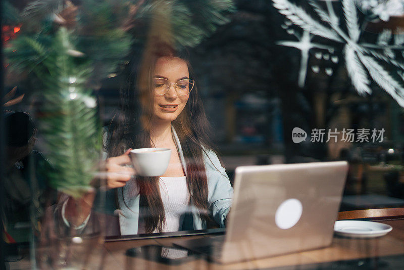 一位年轻女子在咖啡店使用她的笔记本电脑。