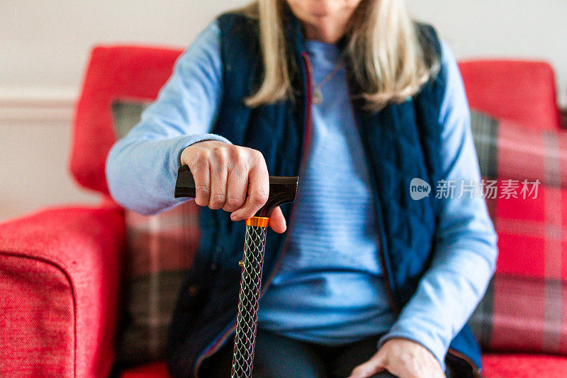 一位老年妇女在家里用手杖养活自己