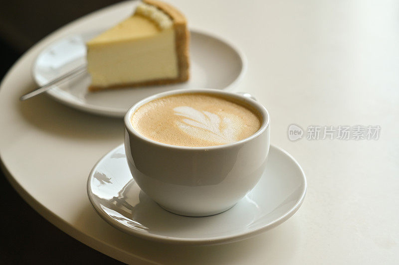 一杯热卡布奇诺拿铁咖啡和一块蛋糕作为早餐。