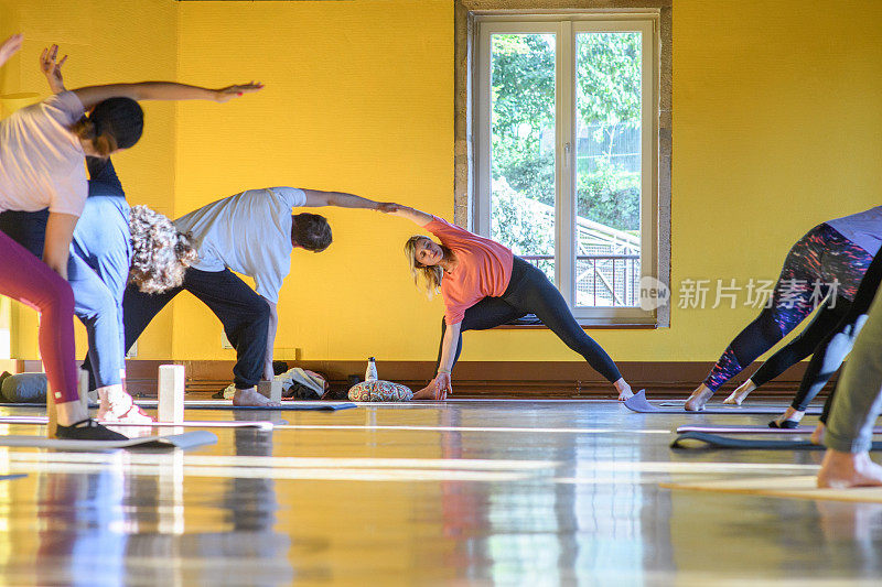 一位瑜伽教练和她的学生一起做一个伸展的侧角姿势