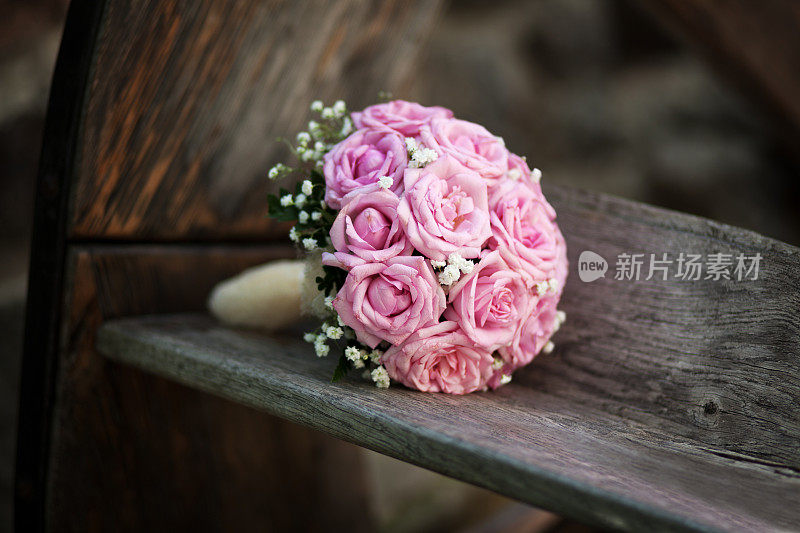 新娘的一束粉色玫瑰放在木凳上