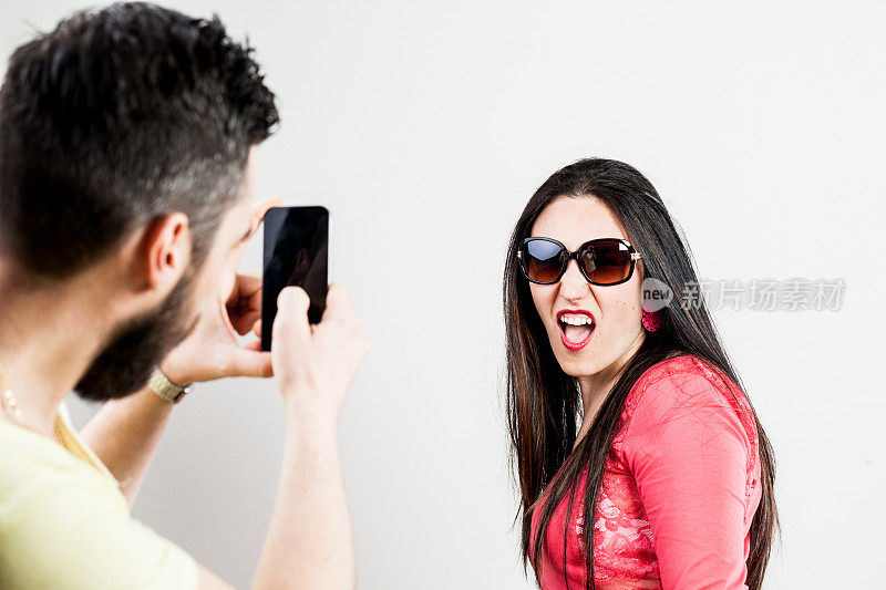 一对激动的情侣用手机拍照和自拍