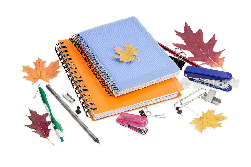 两本笔记本，文具和几片秋叶