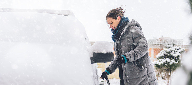 女人打开被雪覆盖的汽车