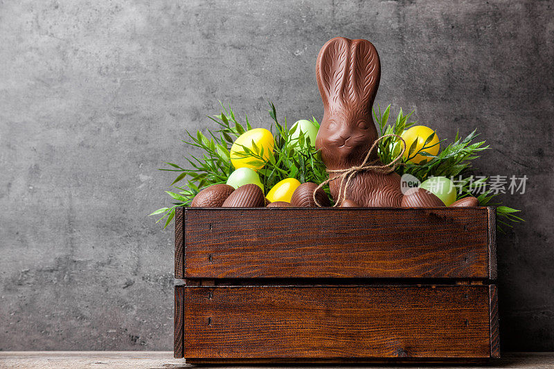 传统的复活节巧克力兔子和鸡蛋装在木箱里