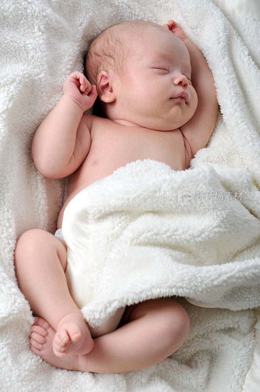 躺在柔软的毯子里的睡着的婴儿