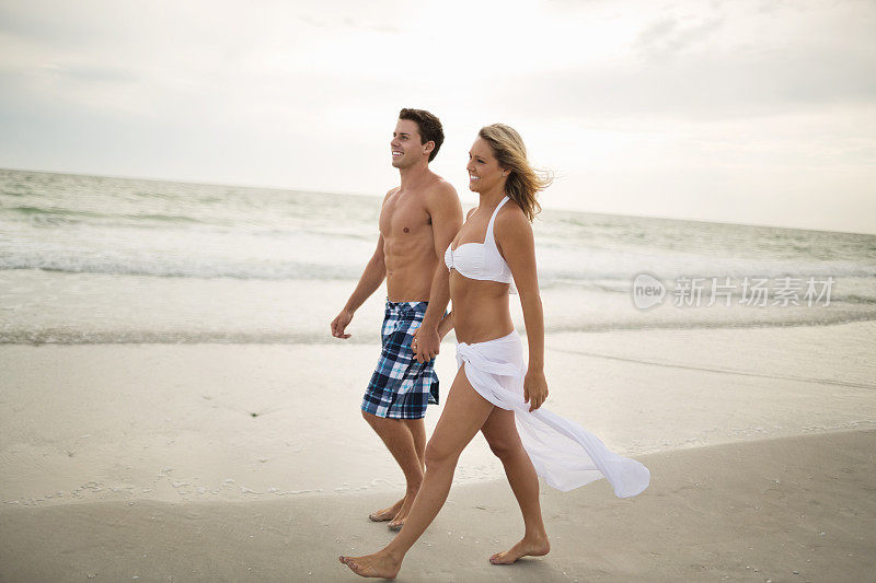 在海滩上牵手散步的幸福夫妇