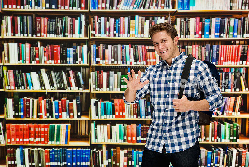 在图书馆微笑的男学生和挥手