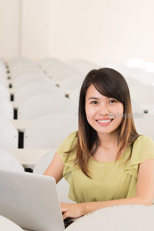 亚洲女孩在教室里用笔记本学习