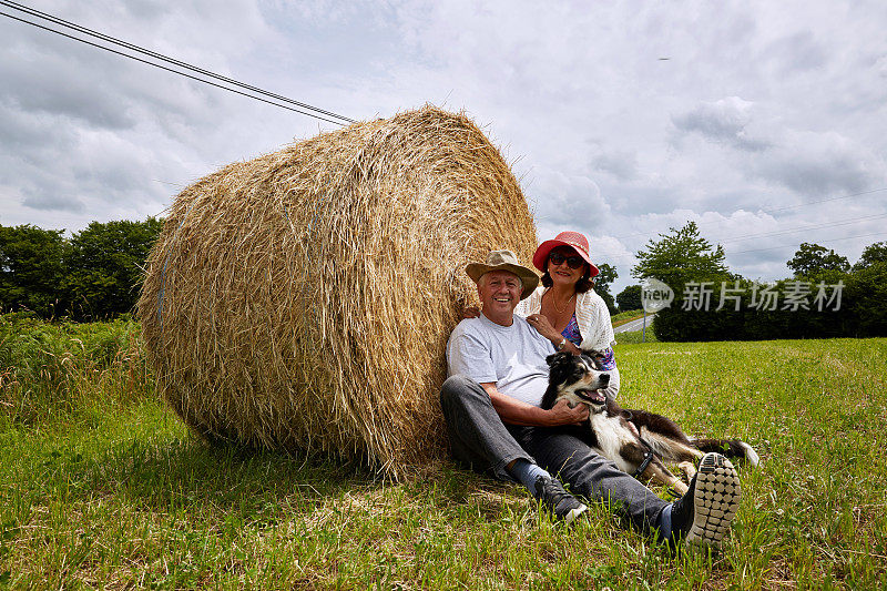 一对成熟的夫妇和一只狗在干草堆上休息