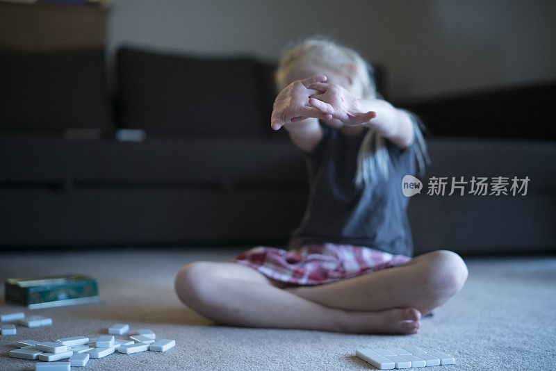 小女孩在地上玩多米诺骨牌