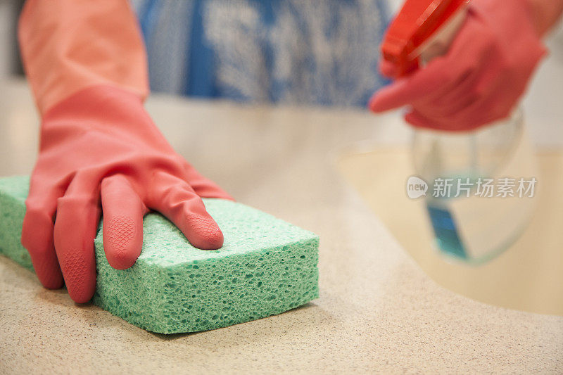 一个妇女正在用海绵和清洁剂清洁厨房。