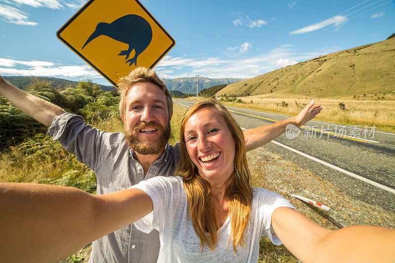 一对夫妇在公路旅行中与新西兰标志自拍