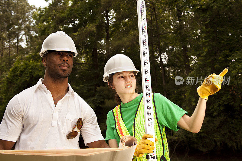 多民族建筑工人，测量员。工作地点。在户外。安全帽。