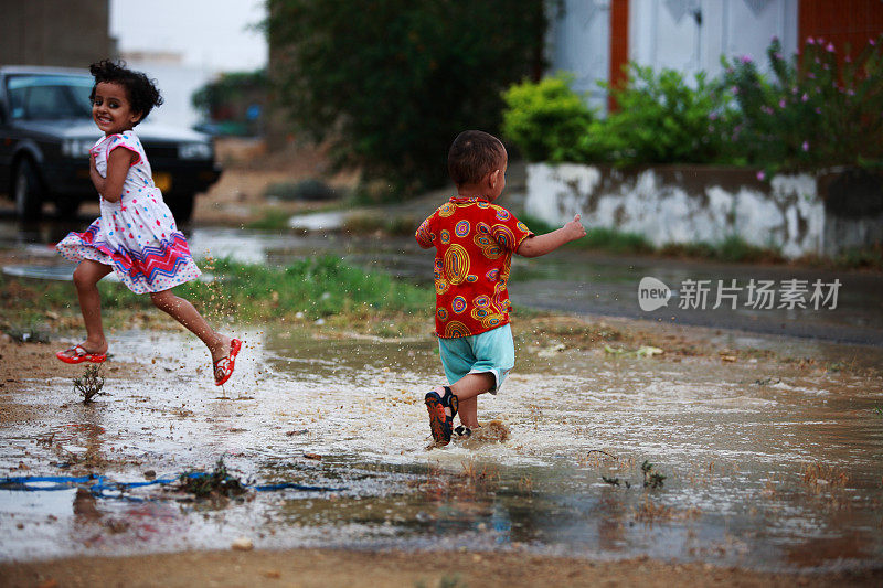 孩子们玩自由雨水水坑溅