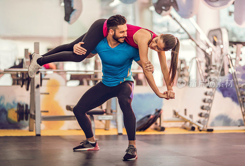 快乐的运动员和他的女朋友在健身房锻炼。