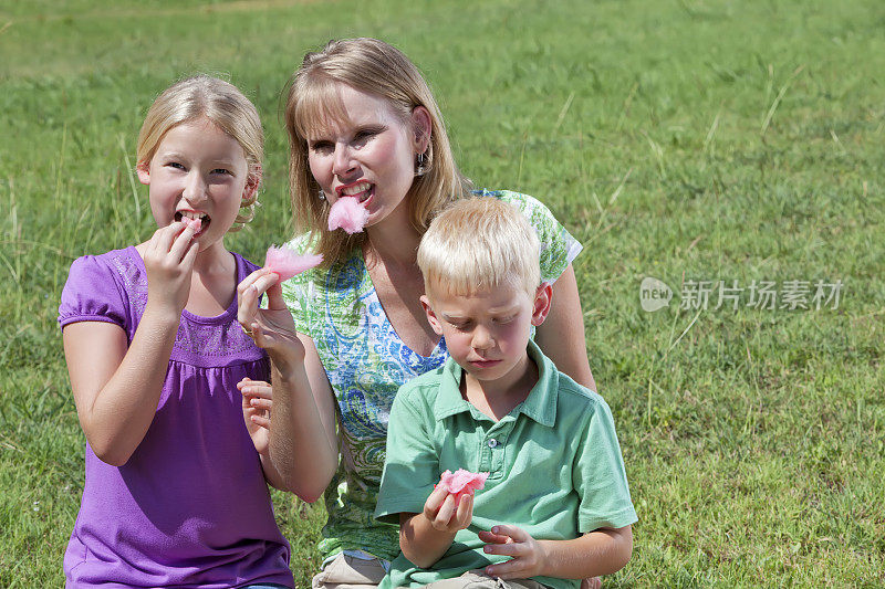 金发家庭在公园吃棉花糖