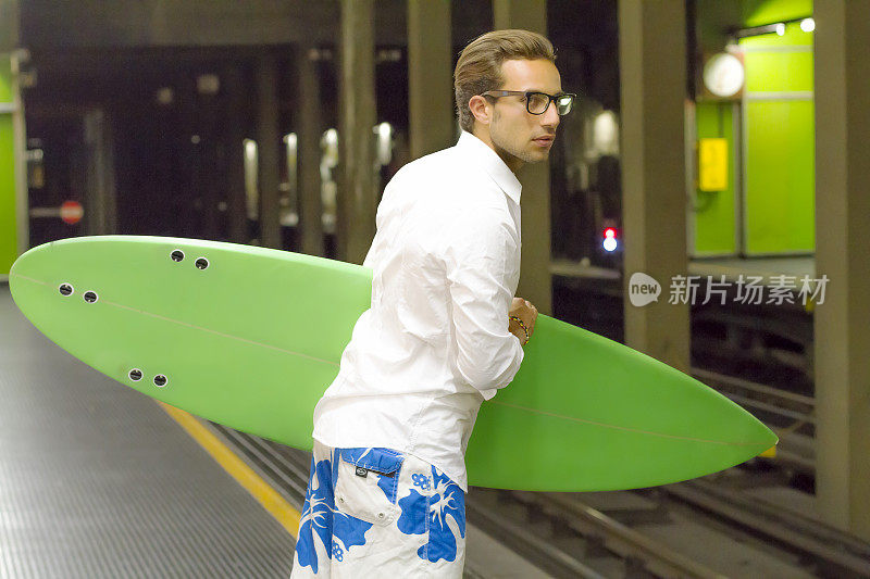 在地铁站里拿着冲浪板的年轻商人