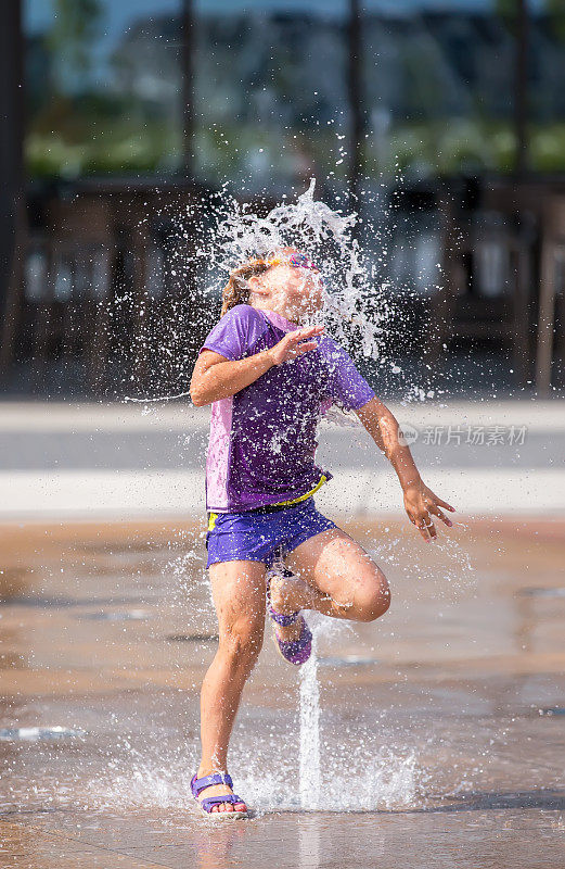 女孩跑过喷泉在户外水花公园