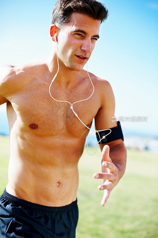 肌肉发达的运动员边慢跑边听音乐
