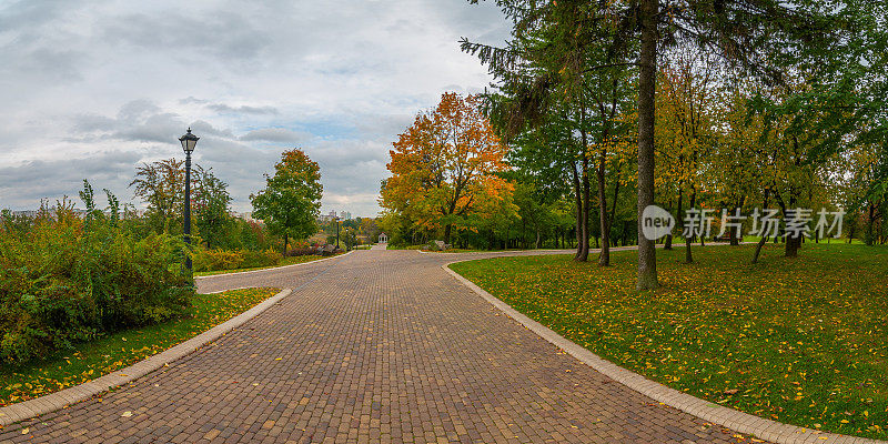 在多云的天空下的一个秋季城市休闲公园里，一条现代的混凝土瓷砖小巷