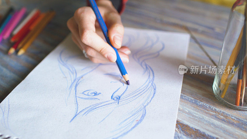 特写的女性手绘素描在纸笔记本与铅笔。工作中的女艺术家