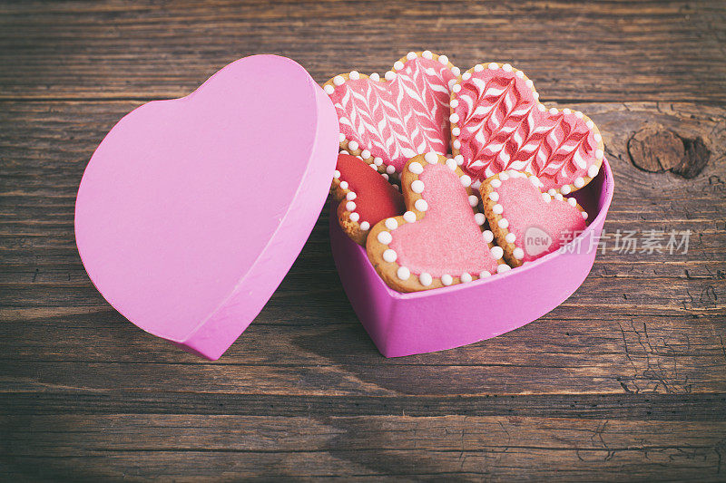 情人节的饼干装在一个心形的盒子里，放在木桌上