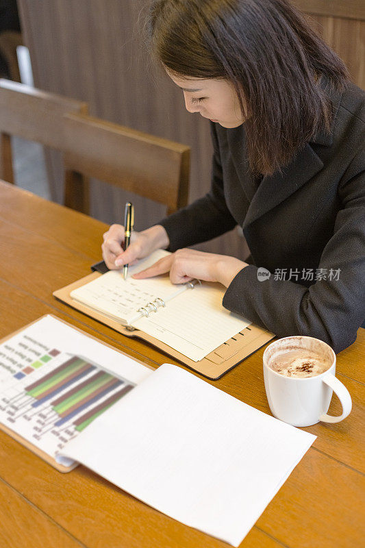 女商人在咖啡馆的桌子上做笔记