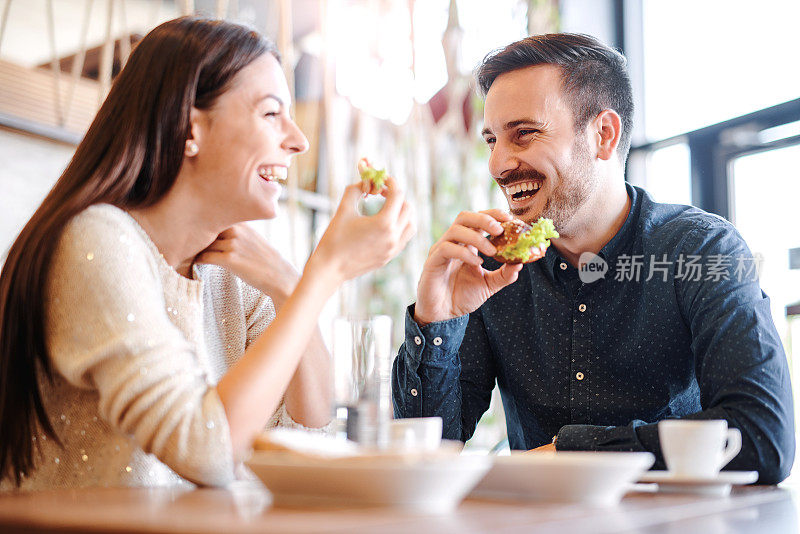 一对年轻漂亮的夫妇坐在咖啡馆里吃早餐。爱,食物,生活方式