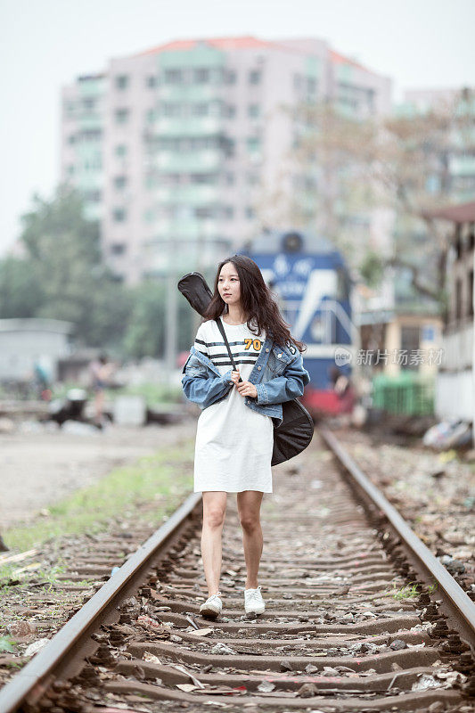 吉他女孩在铁轨上行走。