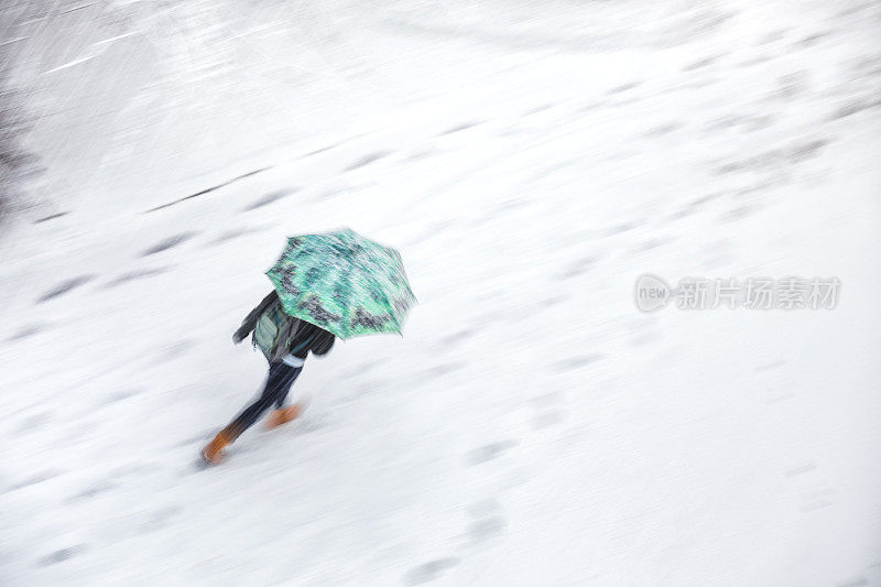 在暴风雪中撑伞行走