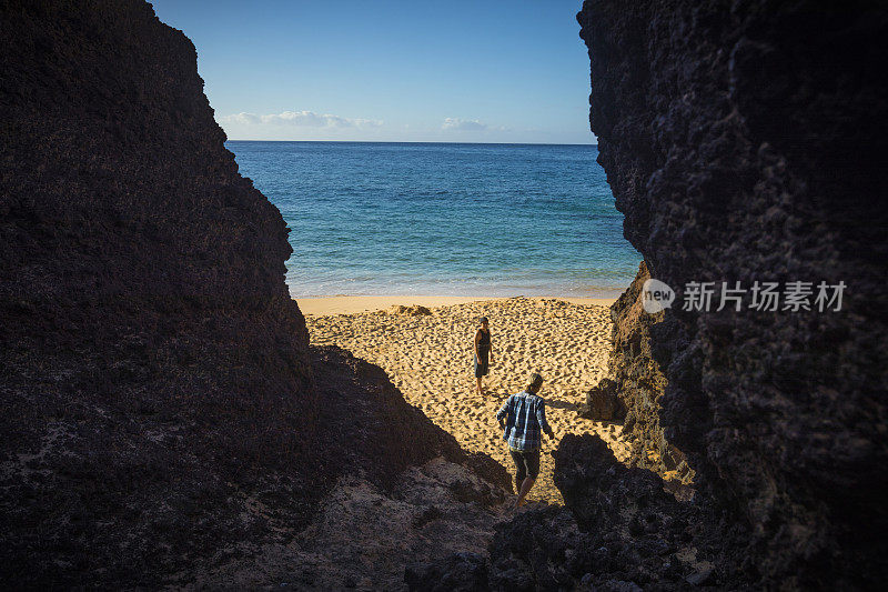 一对情侣在阳光灿烂的日子里独自在毛伊岛的大海滩上。