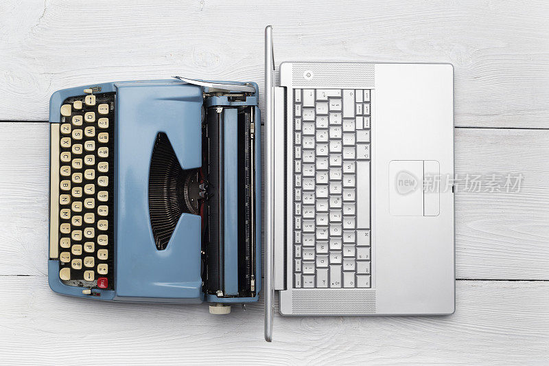 现代笔记本电脑和古董打字机在木桌上