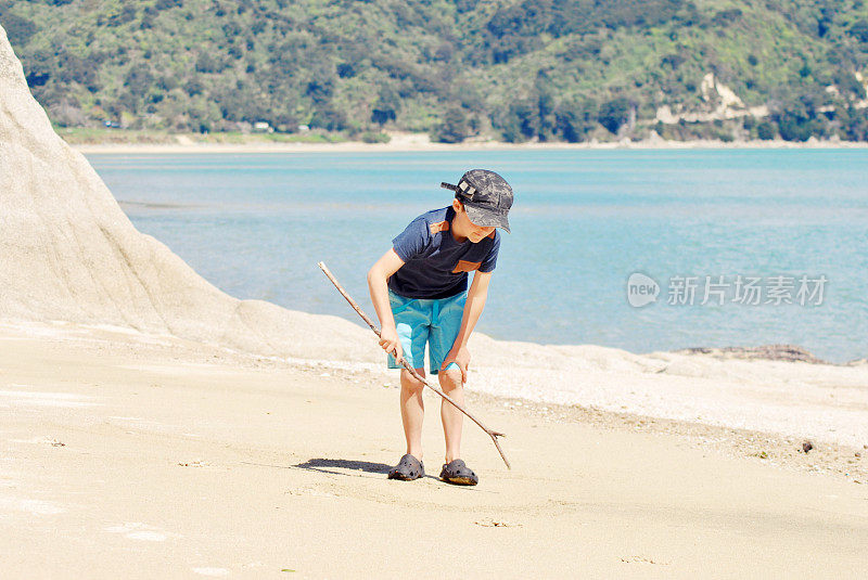 男孩在海滩上玩木棍